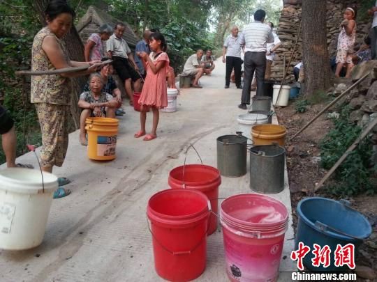  8月4日，村民们守候在一口几近干枯的水井排队等水，村民们称每取一桶水至少要两个小时。　齐永　摄