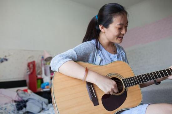 彭晓雯回家后弹着吉他唱起《宝贝》（9月7日摄）。