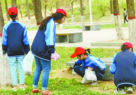 一高校大学生双休日参加文明校园督查活动，正在草坪捡拾垃圾。郑州大学 董健鹏/摄
