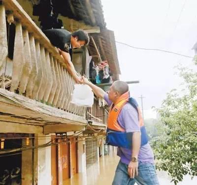 　　7月2日，在广西融安县受灾区，水位缓慢回落之际，当地青年干部正在给受灾群众送去食品。