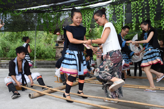 8月8日，谢三英（前左）在瑶山瑶族乡拉片新村和游客一起跳竹竿舞。现在，谢三英在旅游公司内当演员，一个月能有2000余元的收入。