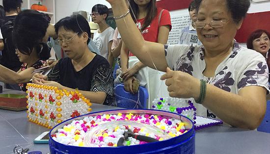 \ “巧手工坊”的志愿者正在编织手工艺品,卖出的收益会纳入公益