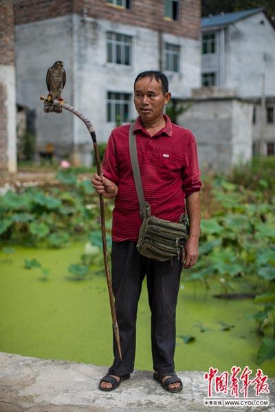 上少寨，57岁的屠户吴朝军举着花508元买来的鹰。他每天往返于寨子和镇子之间。