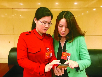 杨彩霞代表（左）向刘文嘉代表展示她手机里“学习型父母群”等各种为工作而建的微信群。