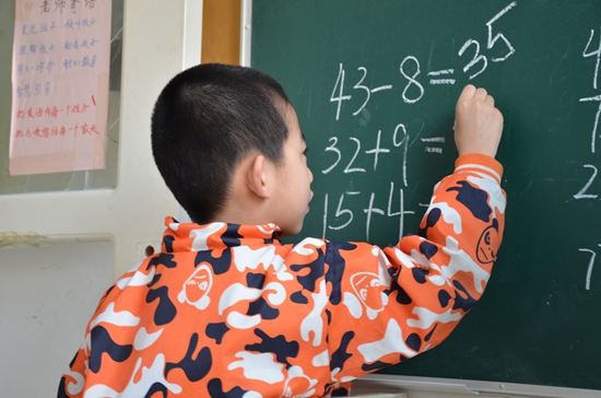 天津“向日葵”自闭症康复中心，一个孩子在黑板上演算。